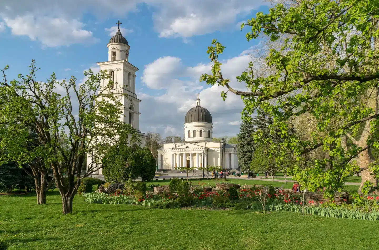 Nativity Cathedral in Chișinău seen from Cathedral Park with the bell tower, green trees, and visitors in the foreground.